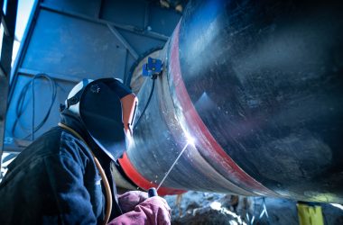 Professional welder welding pipe on a pipeline construction.